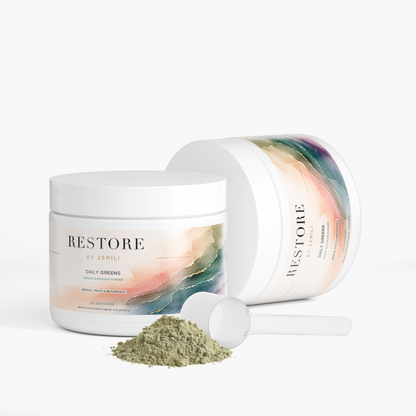 Two Restore by Zerili Daily Greens tubs with a scoop and green powder, one upright and one on its side.